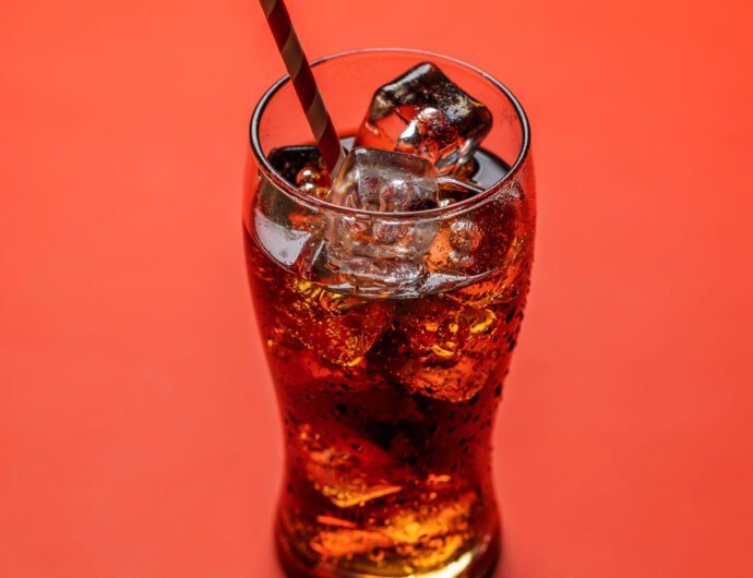 Refreshing glass of cola with ice. Over red background