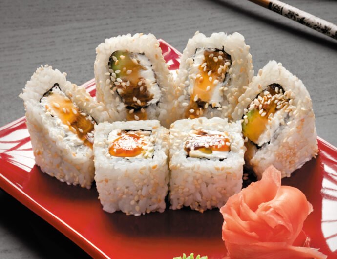 Cream eel. A studio close-up of chopsticks and a square plate with six pieces of eel sushi, wasabi and ginger.