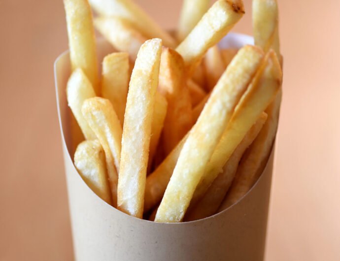Portion of potato chips served in a container Portion of crispy deep fried golden potato chips or French fries served in a container