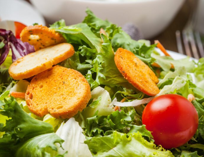Mixed salad with croutons. Mixed salad in white bowl. Selective focus.